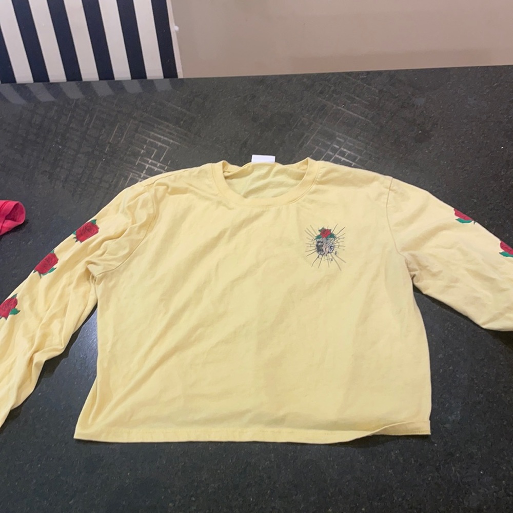 This is a long cropped yellow shirt with roses